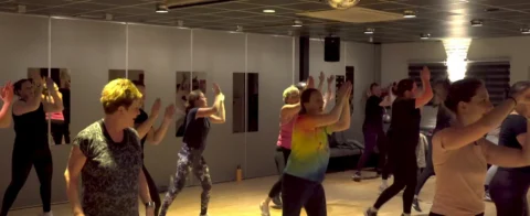 bewegende mensen in danszaal die sportles volgen
